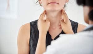 doctor checking thyroid of a young patient in clinic